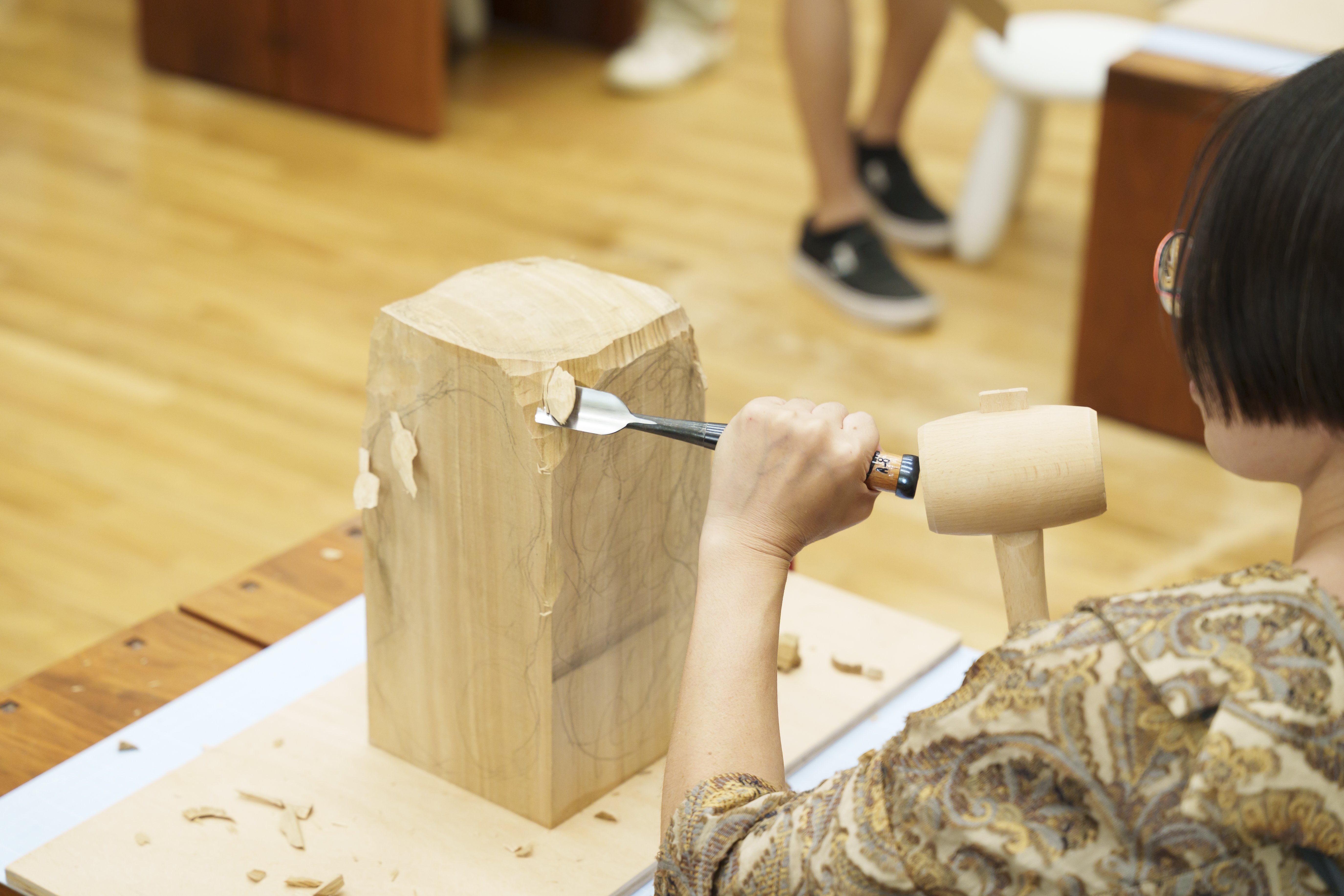 木のかたまりにノミを打ち込んでいる様子