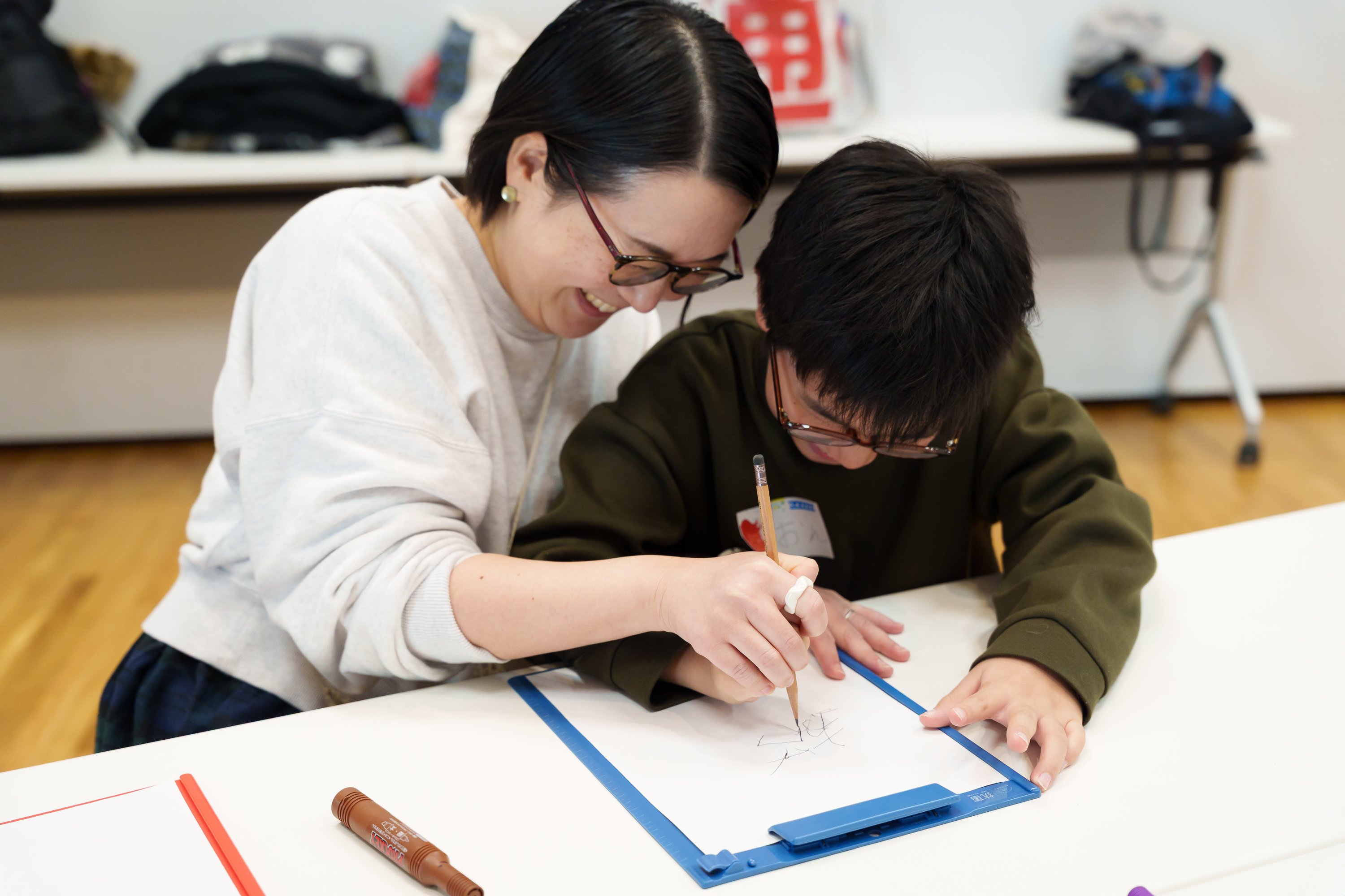 親子で一つの漢字を書いている姿。二人とも笑顔で、楽しそうな様子が伝わってくる